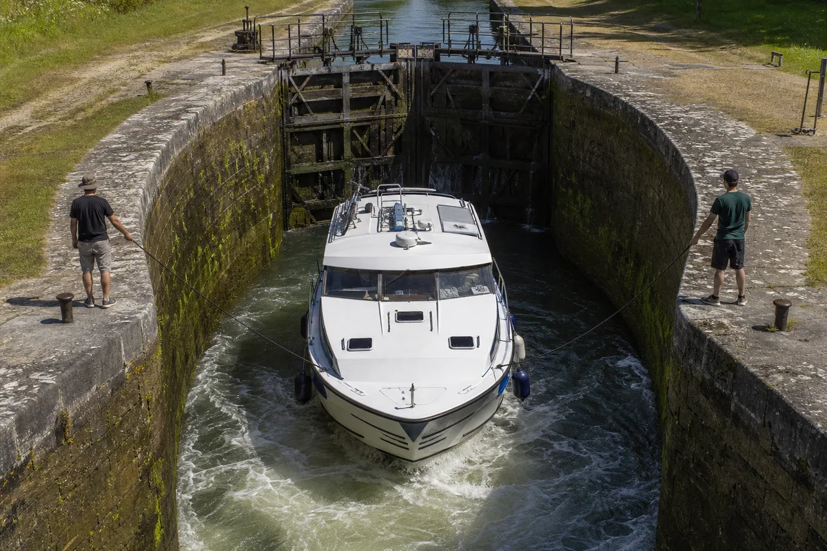 Sas d&rsquo;ecluse ovale du canal du Midi en cours de remplissage, bateau tenu aux amarres par l&rsquo;equipage