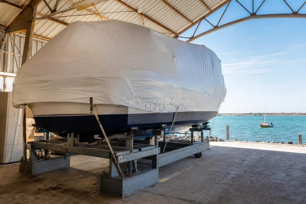 Bateau bache sur son ber de stockage dans un hangar, en hivernage
